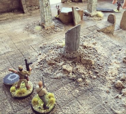 28mm Hand‑Built Scenic Building Terrain Two miniature soldiers stand near a stone pillar in a detailed terrain setting.